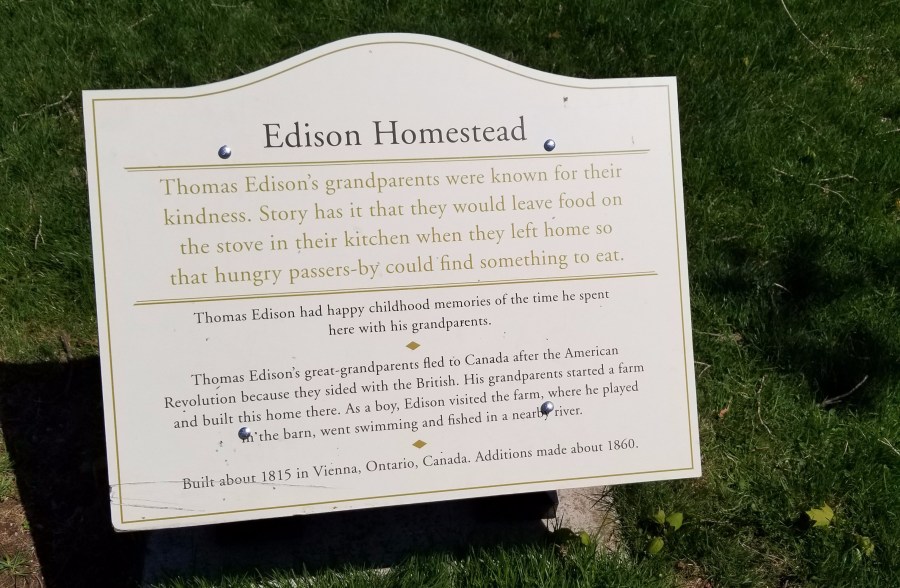 The plaque outside the Edison Homestead at Greenfield Village. The text reads: "Edison Homestead "Thomas Edison's grandparents were known for their kindness. Story has it that they would leave food on the stove in their kitchen when they left home so that hungry passers-by could find something to eat. "Thomas Edison had happy childhood memories of the time he spent here with his grandparents. "Thomas Edison's great-grandparents fled to Canada after the American Revolution because they sided with the British. His grandparents started a farm and built this home there. As a boy, Edison visited the farm, where he played in the barn, went swimming and fished in a nearby river. "Built about 1815 in Vienna, Ontario, Canada. Additions made about 1860."